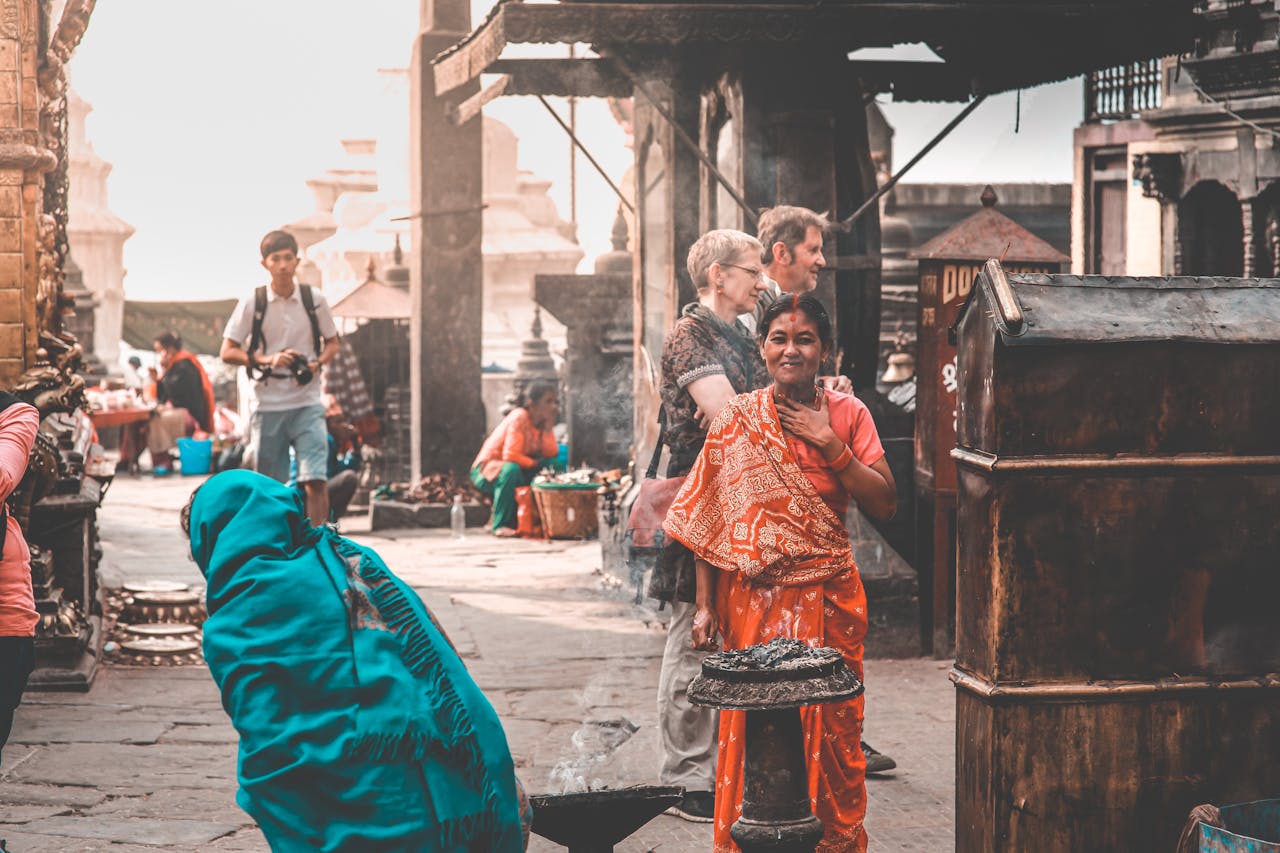 Local Nepali people in traditional clothes and travelers walking on paved street of old town on sunny day